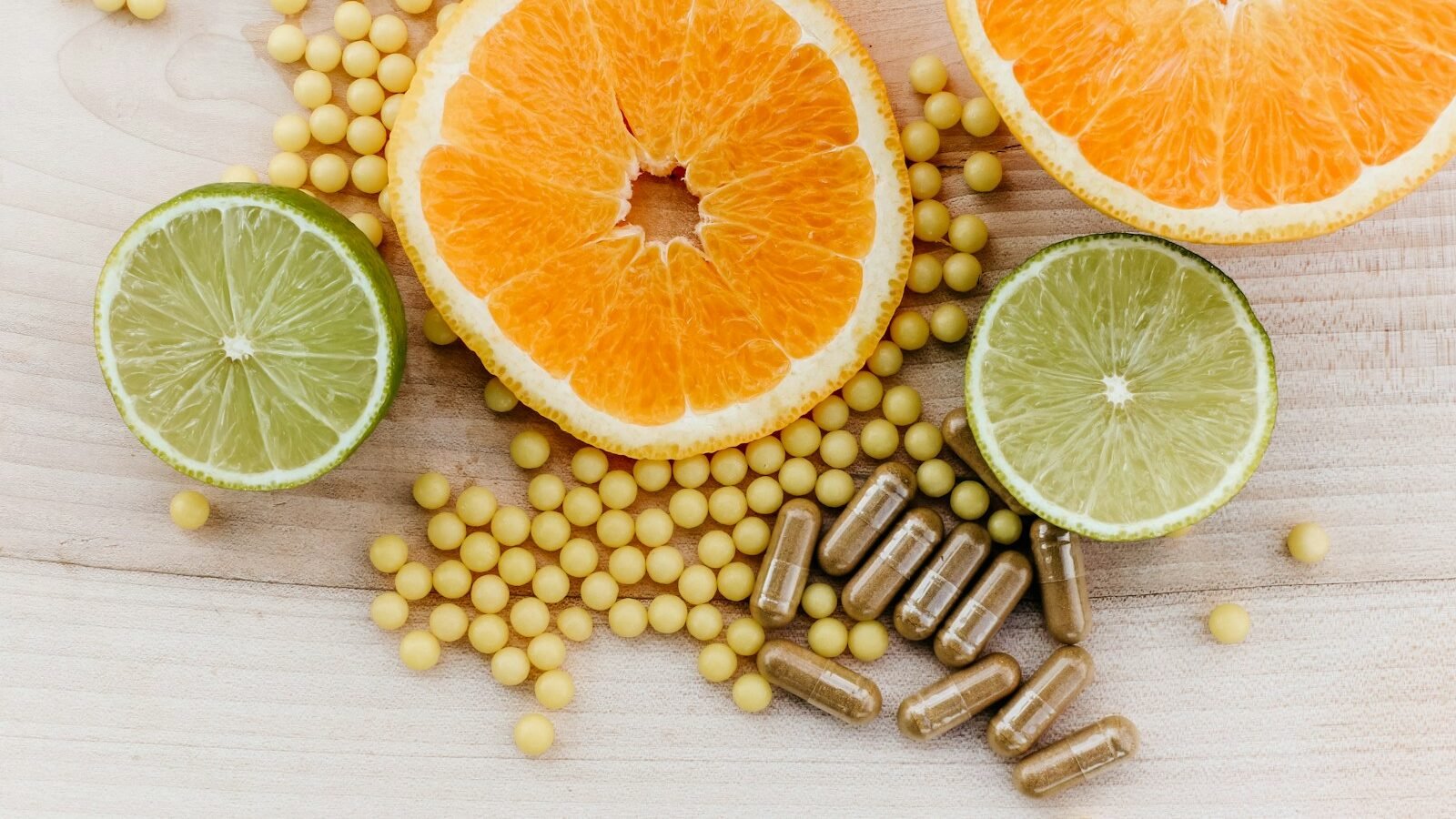 oranges, peas, and limes on a wooden table with skin supplements.