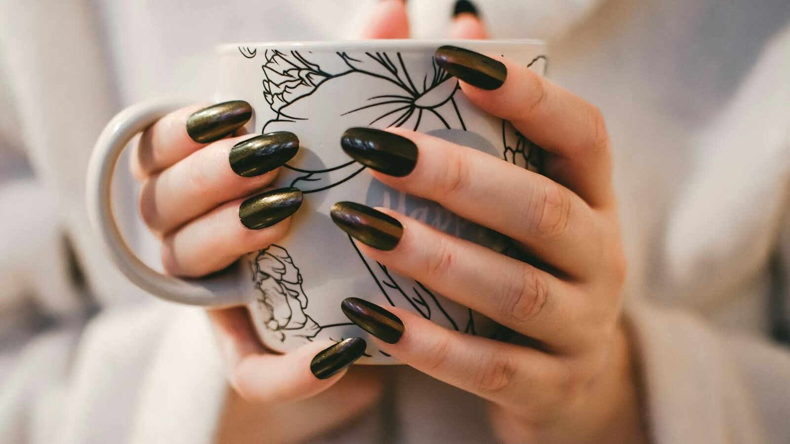 A close-up of manicured hands holding a decorative mug, perfect for lifestyle and coffee themes.