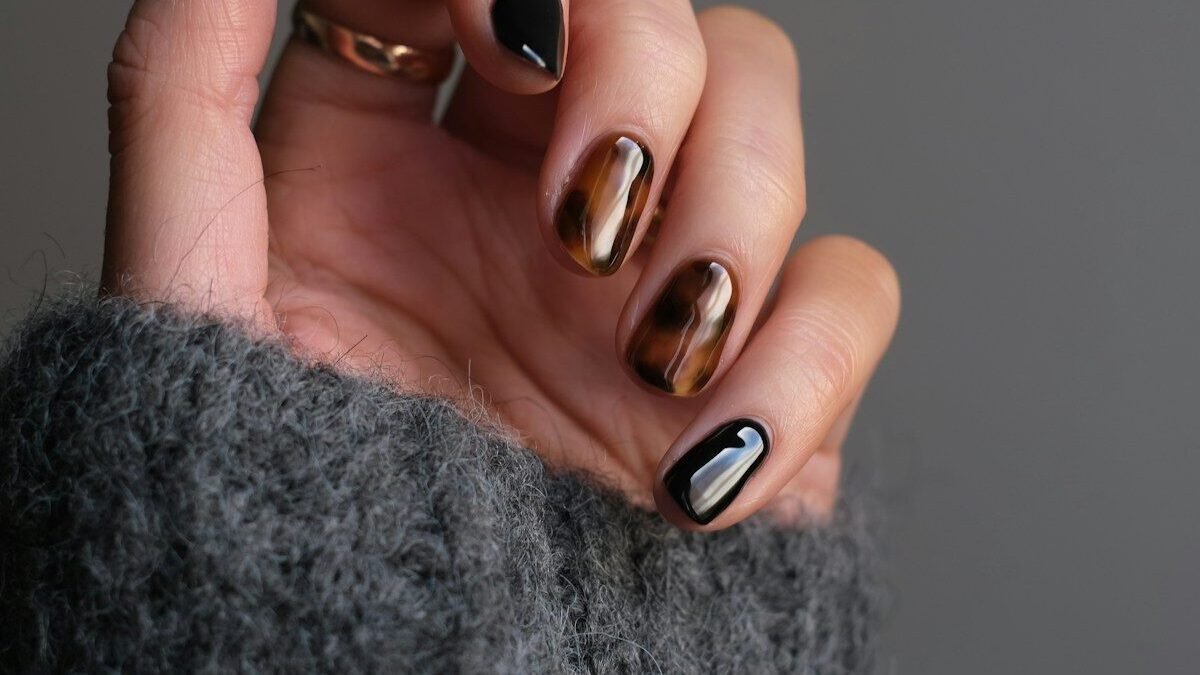 person wearing silver ring with black manicure
