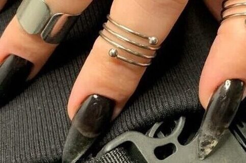 a woman's hand with black nail polish on it