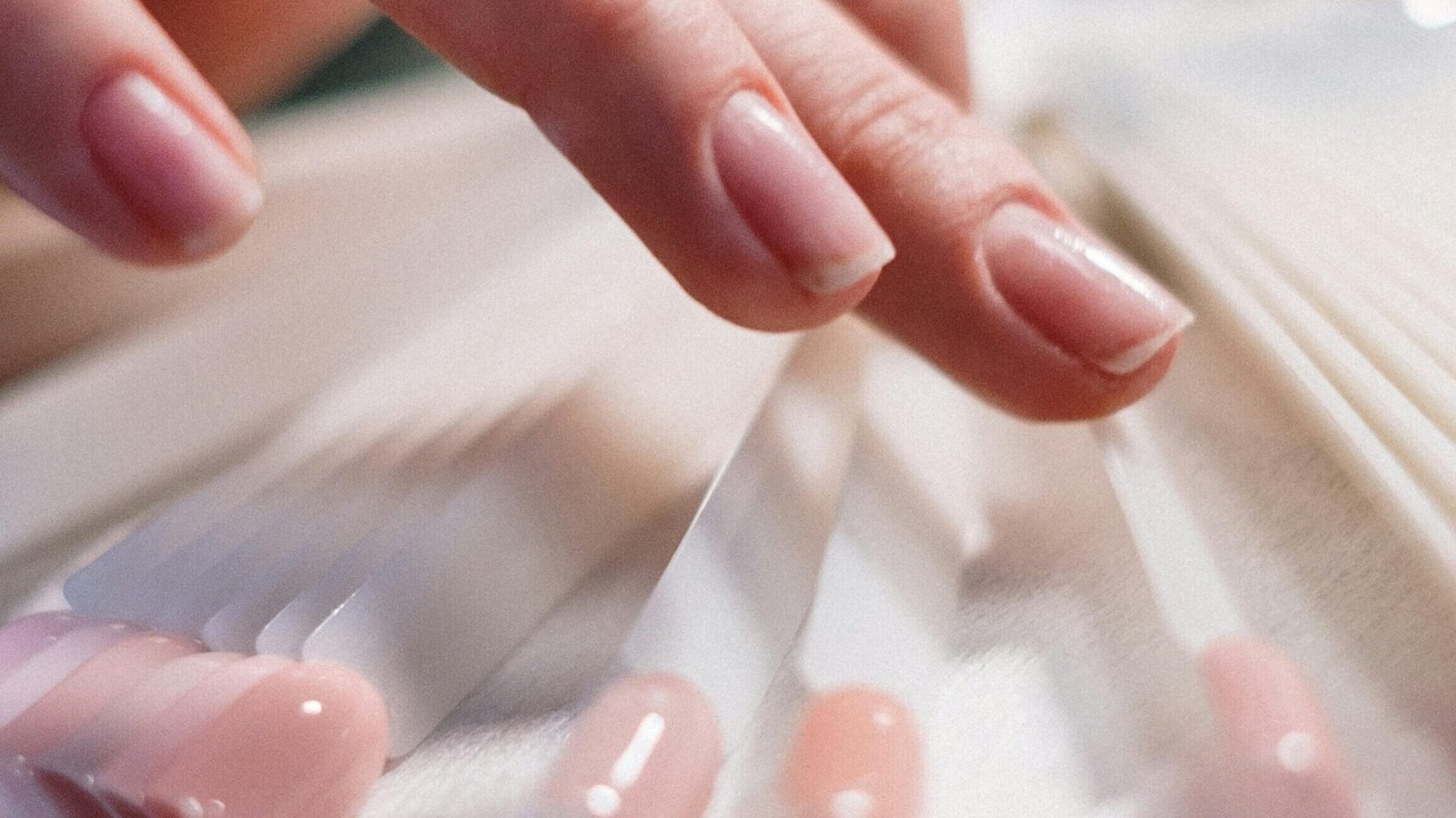 Hands holding samples of premium acrylic nails from a beauty product guide.