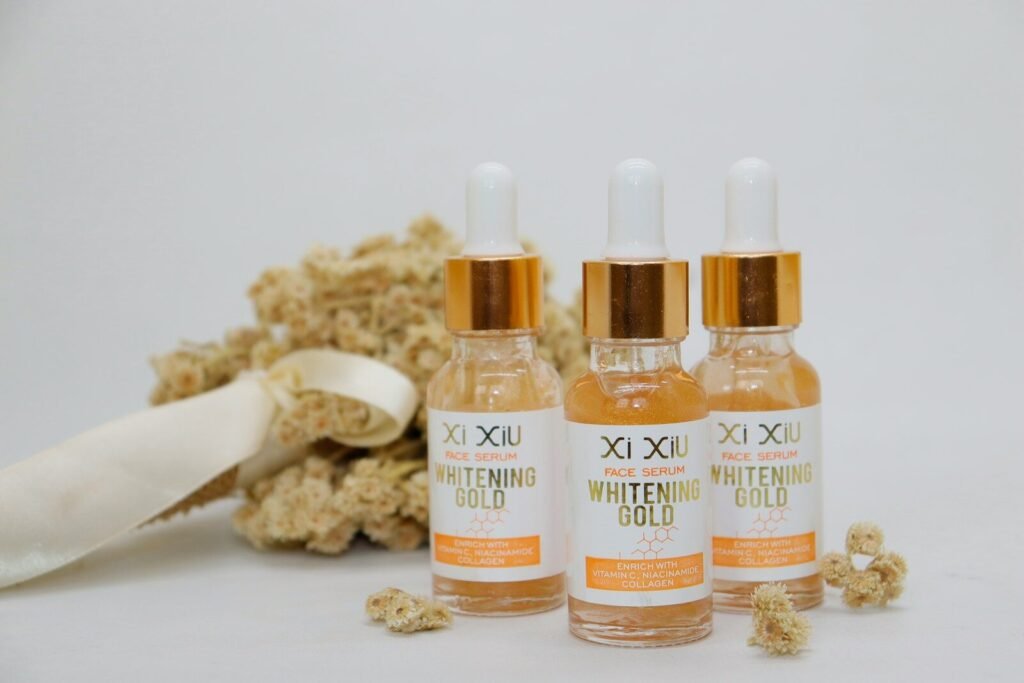three bottles of whitening gold sitting next to some flowers